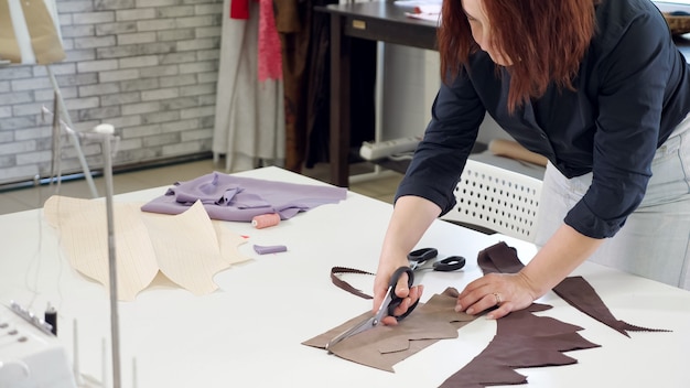 Foto taglio e cucito di prodotti nel settore della sartoria. dettagli di taglio donna su misura da tessuti lavora in attività di laboratorio di sartoria. taglio con le forbici a zig zag. sarta creando un nuovo prodotto.