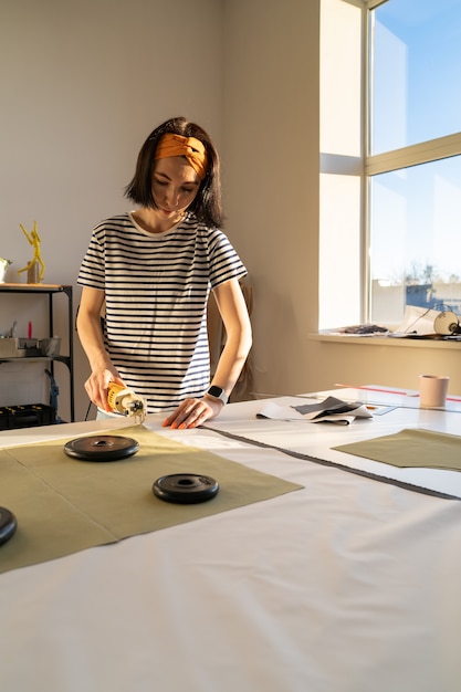 Cutting and sewing in tailor studio sewer young woman work with fabric in design workshop studio