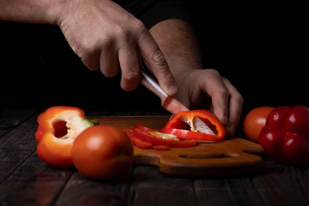 野菜を切る 男性の手が切り板で甘い赤い胡<unk>を切る