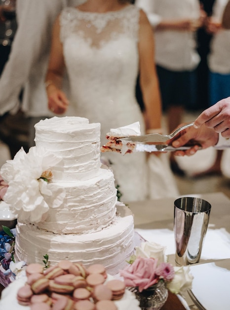 Cutting a white wedding threetiered cake