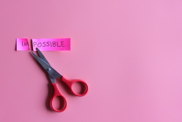 Photo cutting the word impossible to possible on pink background self belief positive attitude motivation