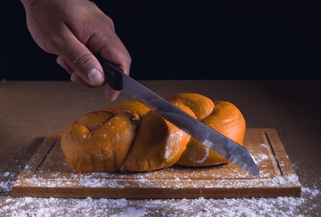 cutting yellow bread on the table with knife