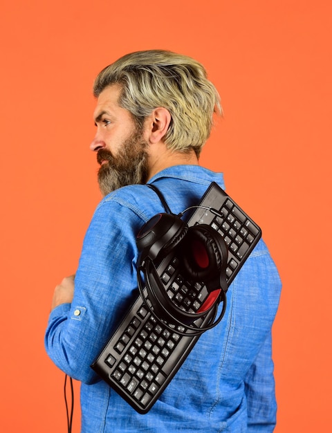 インターネットから音楽をダウンロードするサイバー選手権アジャイル ビジネスひげを生やした男のヘッドフォンとキーボード プロのゲーマー アーケード コンピューター ゲーム チャット オンライン オンライン ビデオ ゲーム
