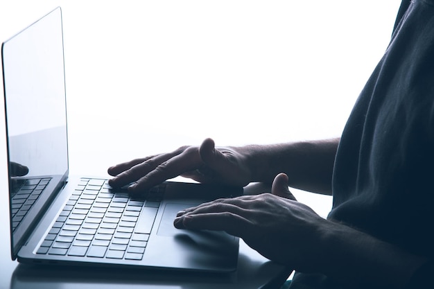 Концепция киберпреступности с копировальным пространством Анонимный мужчина использует ноутбук с обратным освещением
