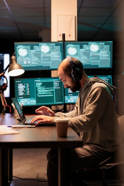 사이버 범죄자는 컴퓨터 서버를 해킹하려고 하고 헤드폰을 끼고 밤 늦게까지 일합니다. 해커가 보안 시스템에 침입하여 정보를 훔치고, 비밀번호를 해킹하고, 맬웨어를 작성합니다.