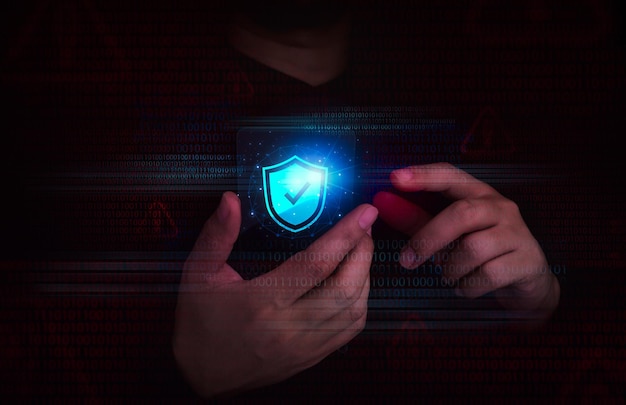 Cyber security technology and data protection privacy concepts Shield icon on futuristic transparent smart mobile phone in hand surrounded with binary code and malware icon alert on dark background