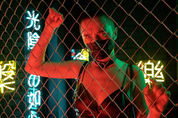 Cyberpunk girl with leather tank top standing behind the bars with neon hieroglyphs meaning nirvana and western paradise