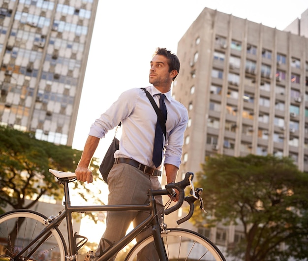 Foto pendolarismo in bicicletta e uomo d'affari in città per emissioni mattutine a emissioni zero e trasporto professionista sostenibile e viaggio con impiegato maschio che cammina con la bicicletta in città urbana per viaggio e viaggio