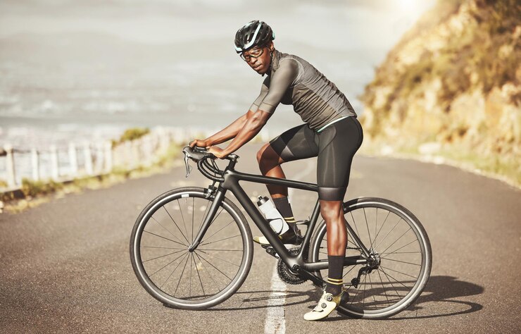 Photo cycling energy and bike cyclist in a road along a mountain power focus and mindset in south africa sports fitness and marathon training with black man riding along views of the city on a bicycle