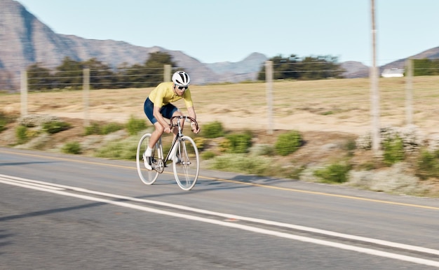 Велоспорт фитнес и человек с велосипедом на дороге вызов и действия с велотренажером на открытом воздухе и шлем для безопасности Верховая езда спортсмена и подготовка к гонке или триатлону с велосипедом
