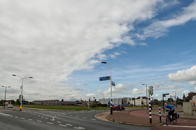 A cyclist awaits a traffic signal on a highway in Vlaardingen on a sunny day