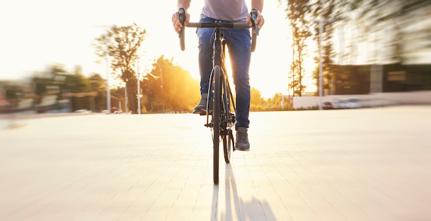 The cyclist in casual clothing riding the bicycle in the evening