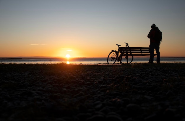 Cyclist contemplating the sunrise in the winter on the waterfront street of galway