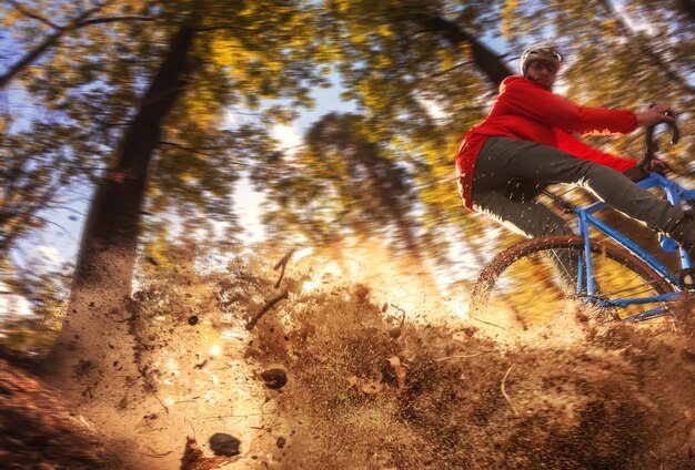 Cyclist in the forest rides along the trail, raising up dust from the rear wheel after a skid.