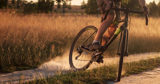 자갈 자전거를 탄 자전거 타는 사람은 비포장 도로를 타고 뒷바퀴에서 먼지를 들어올립니다.