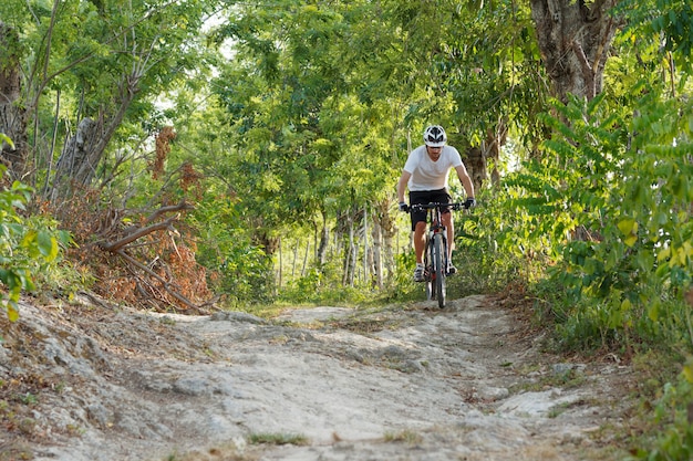 The cyclist is riding on mountain bike on rocks trail in forest