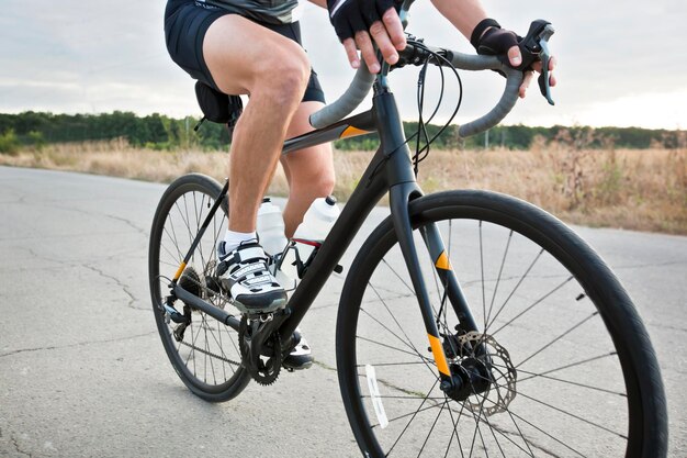 The cyclist is training on his road bike outside the city by asphalt road