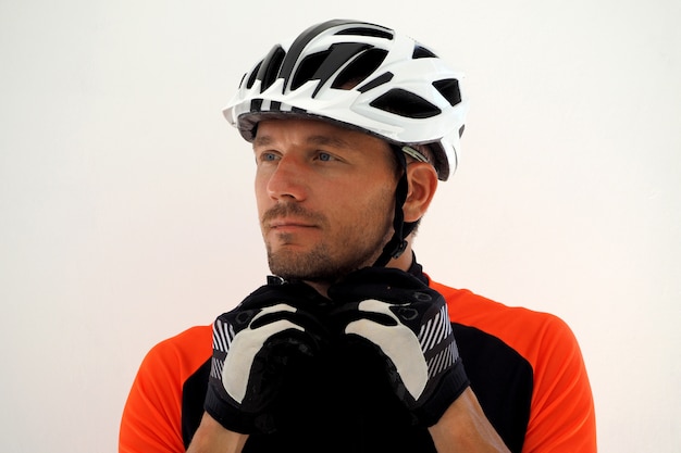 Cyclist in jersey fastens the straps on his helmet. Close up portrait.