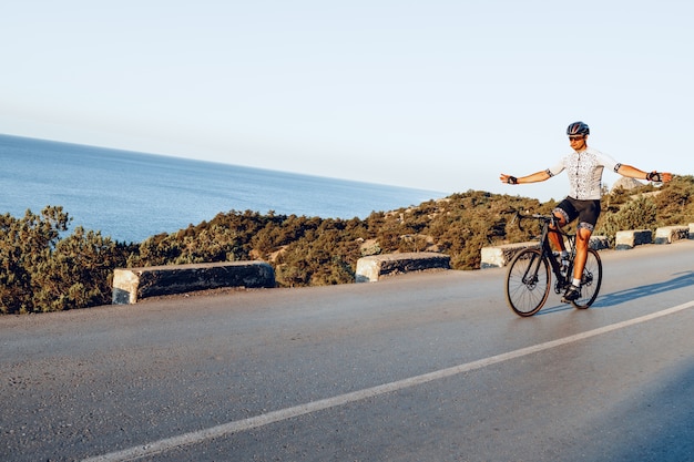 Cyclist man riding on coastal road at dawn