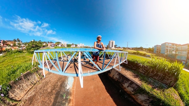 Cyclist man with helmet and bicycle on lake bridge in a sunny blue sky day