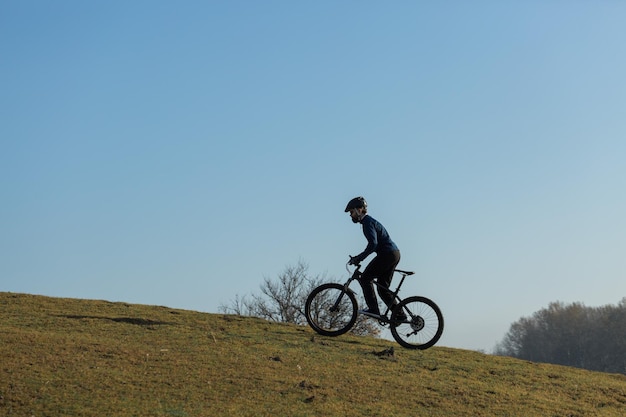 Cyclist in pants and fleece jacket on a modern carbon hardtail bike with an air suspension fork The guy on the top of the hill rides a bike