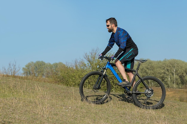 Cyclist in pants and fleece jacket on a modern carbon hardtail
bike with an air suspension fork rides offroad the guy is resting
on a bench in the autumn park