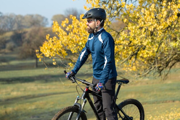 Il ciclista in pantaloni e giacca in pile su una moderna bici hardtail in carbonio con forcella a sospensione pneumatica percorre fuoristrada