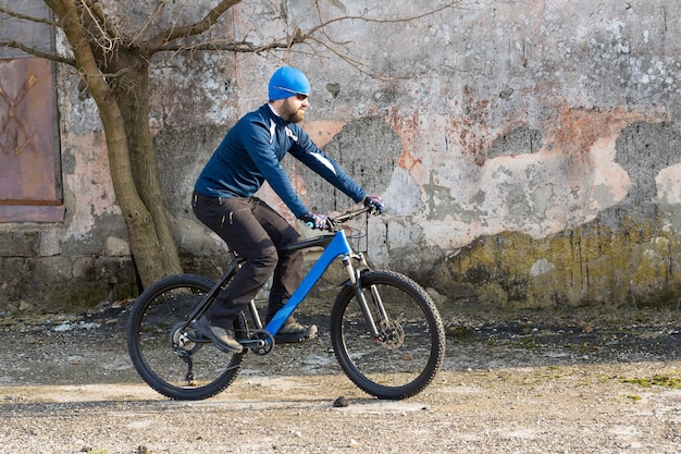 Il ciclista in pantaloni e giacca in pile su una moderna bici hardtail in carbonio con forcella a sospensione pneumatica percorre fuoristrada