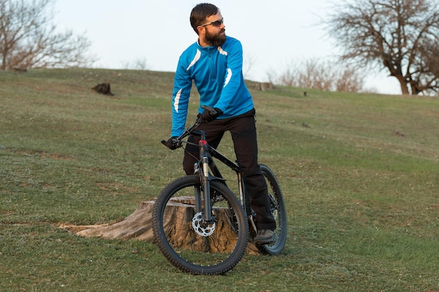 Велосипедист в штанах и флисовой куртке на современном карбоновом хардтейле с вилкой с пневматической подвеской
