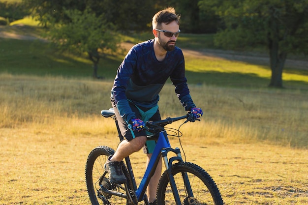 サスペンションフォークがオフロードに乗るモダンなハードテイルバイクのパンツとフリースジャケットのサイクリスト