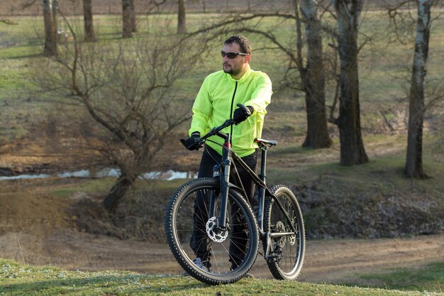 Cyclist in pants and green jacket on a modern carbon hardtail bike with an air suspension fork The guy on the top of the hill rides a bike