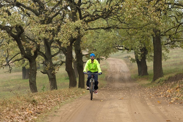 Велосипедист в брюках и зеленой куртке на современном карбоновом хардтейле с вилкой с пневматической подвеской