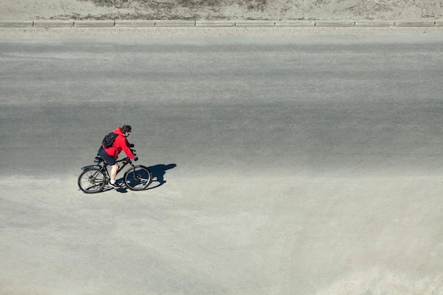 Велосипедист в красной куртке едет по дороге
