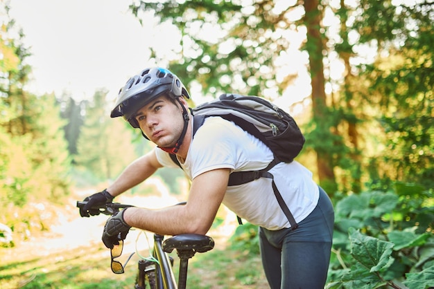 Cyclist resting after strenuous bike ride on forest roads