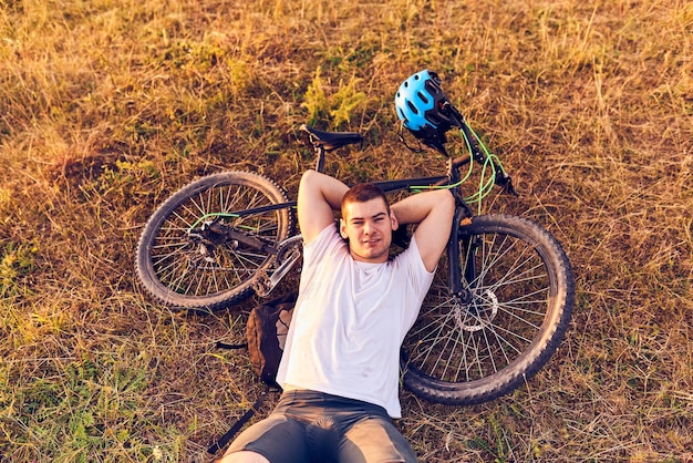 Cyclist resting after strenuous bike ride on forest roads