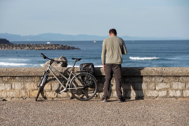 Ciclista in appoggio guardando al mare