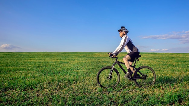 The cyclist rides a bicycle on the green grass on the field. Outdoor sports. Healthy lifestyle.