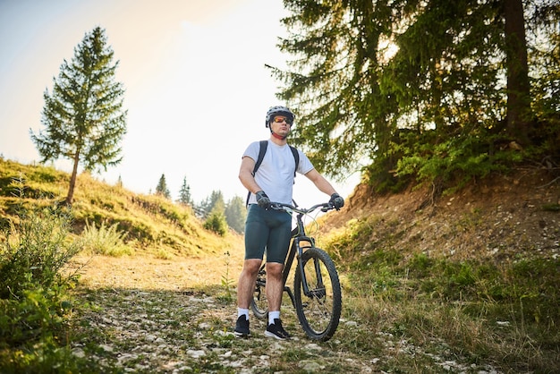 サイクリストは、林道を通って彼の隣に自転車に乗ります