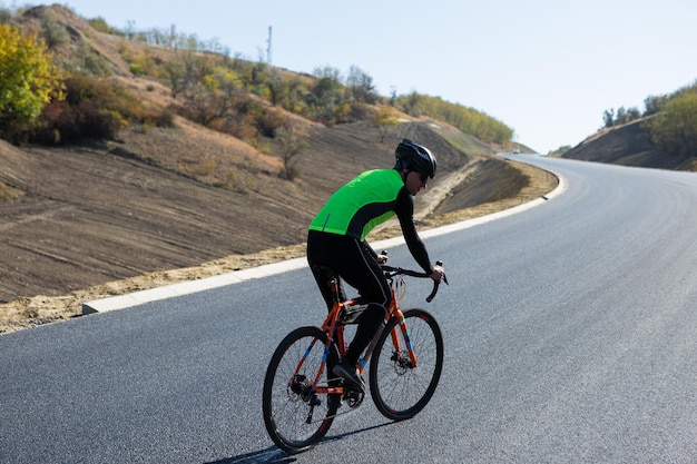 写真 明るい空の向こうの道路で自転車に乗っているサイクリスト