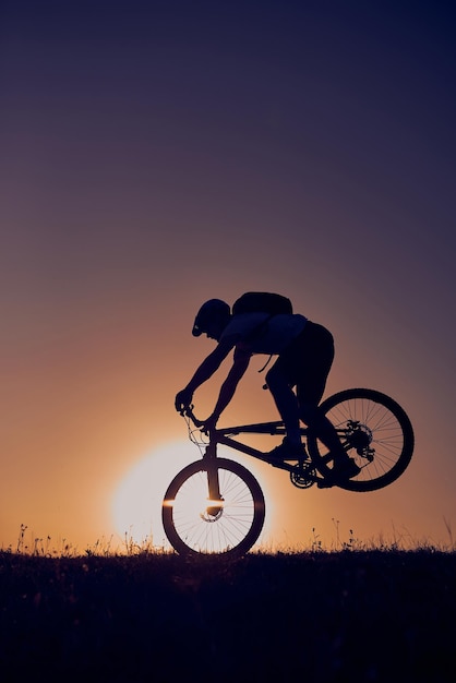 A cyclist riding a bike on a mountain at sunset