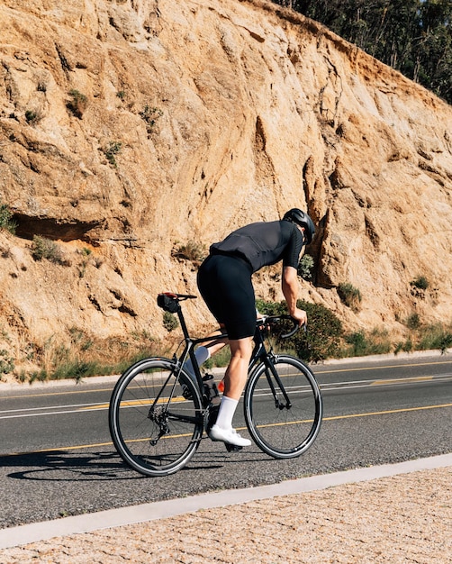 Foto ciclista in sella alla sua bicicletta su una strada di montagna