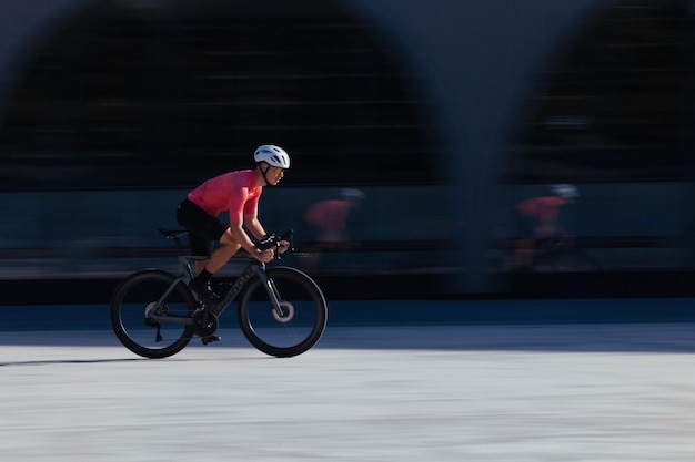 Photo cyclist riding up hill in red kit