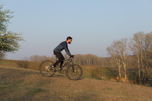 Cyclist in shorts and jersey on a carbon hardtail bike with an suspension fork standing on a cliff