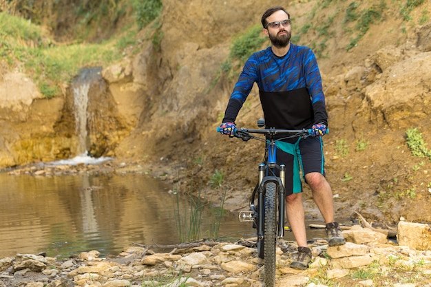 Ciclista in pantaloncini e maglia su una moderna bici hardtail in carbonio con forcella a sospensione pneumatica