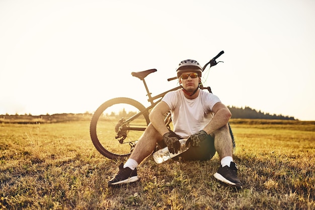 자전거 타는 사람은 산길을 힘겹게 달리다가 풀밭에 앉아 쉬고 있습니다. 선택적 초점. 고화질 사진