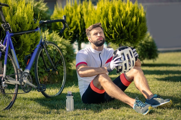 自転車の近くの芝生の上に座っているサイクリスト