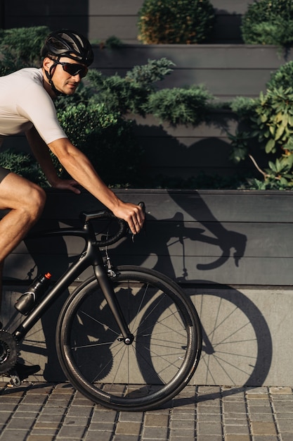 Cyclist in sport clothes riding black bike on city street