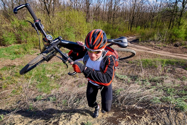 Un ciclista in abbigliamento sportivo con una bicicletta nel parco.