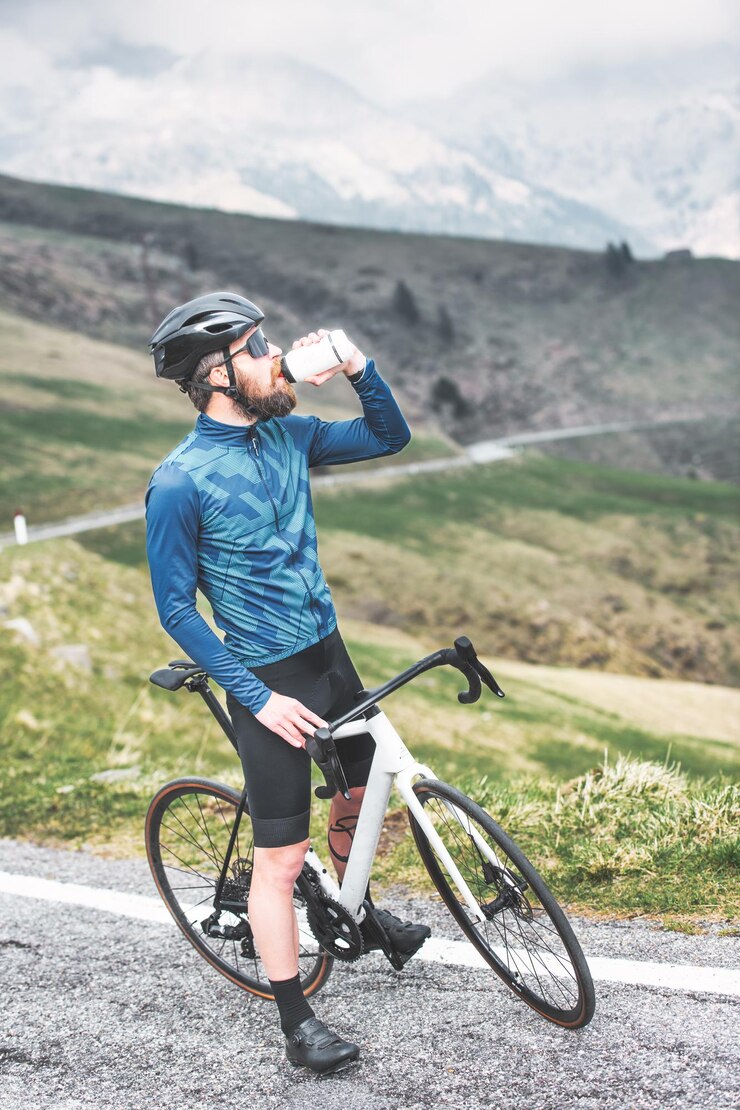 自転車に乗っている人が立ち止まり、水筒から飲み物を飲む