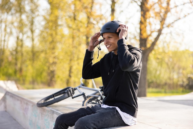 Cyclist who fell off his bike a bmx and is sitting on a\
concrete ramp prepares to get back on track